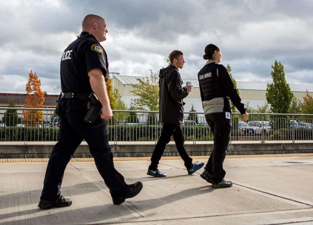 Officer Justin Springs (left) and social worker Elisa Delgado escort Oliver Gerds to his bus to Spokane on Thursday in Everett. (Olivia Vanni / The Herald)

