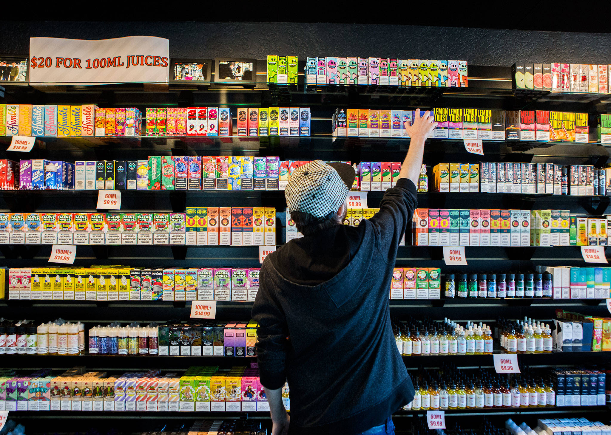 Employee Marcus Esmay reaches for a container of vape juice on Oct. 1 at a store in Everett. (Olivia Vanni / The Herald)