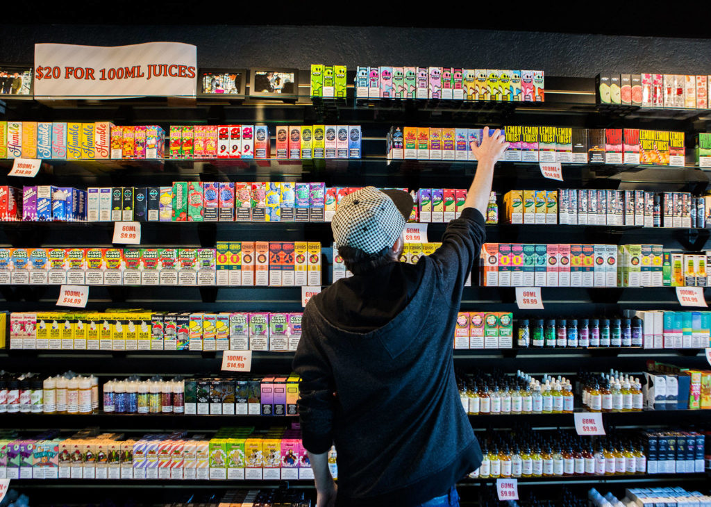 Employee Marcus Esmay reaches for a container of vape juice on Oct. 1 at a store in Everett. (Olivia Vanni / The Herald)
