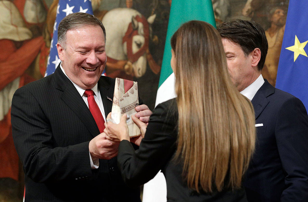 U.S. Secretary of State Mike Pompeo is given a package of Parmesan cheese as Italian Premier Giuseppe Conte (right) looks on, following their meeting at Chigi Palace premier’s office in Rome on Tuesday. (AP Photo/Andrew Medichini)