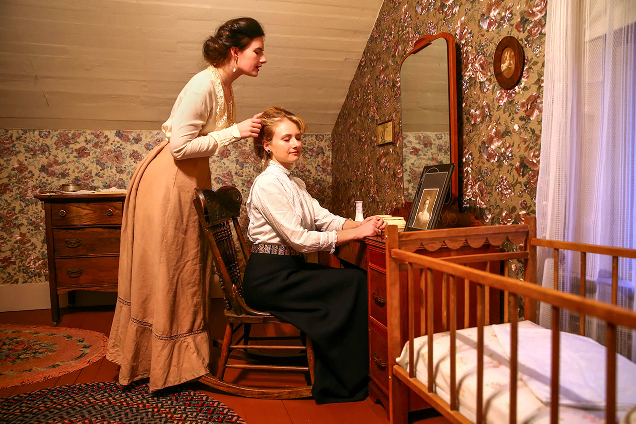 Autumn (left) and Emerald Adams primp in an upstairs bedroom at the Grimm House. (Kevin Clark / The Herald)