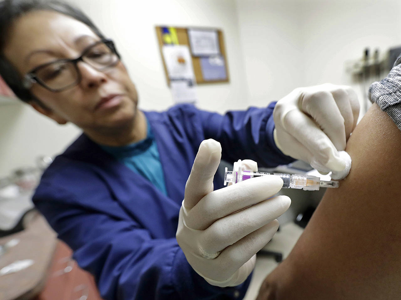 In this 2018 photo, Ana Martinez, a medical assistant at the Sea Mar Community Health Center, gives a patient a flu shot in Seattle. (AP Photo/Ted S. Warren)