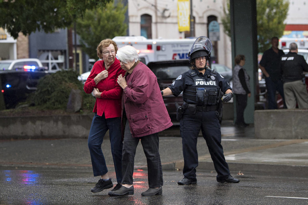 Women evacuate from Smith Tower Apartments with the help of law enforcement following an active shooter situation in downtown Vancouver, Washington, on Thursday. (Amanda Cowan/The Columbian via AP)
