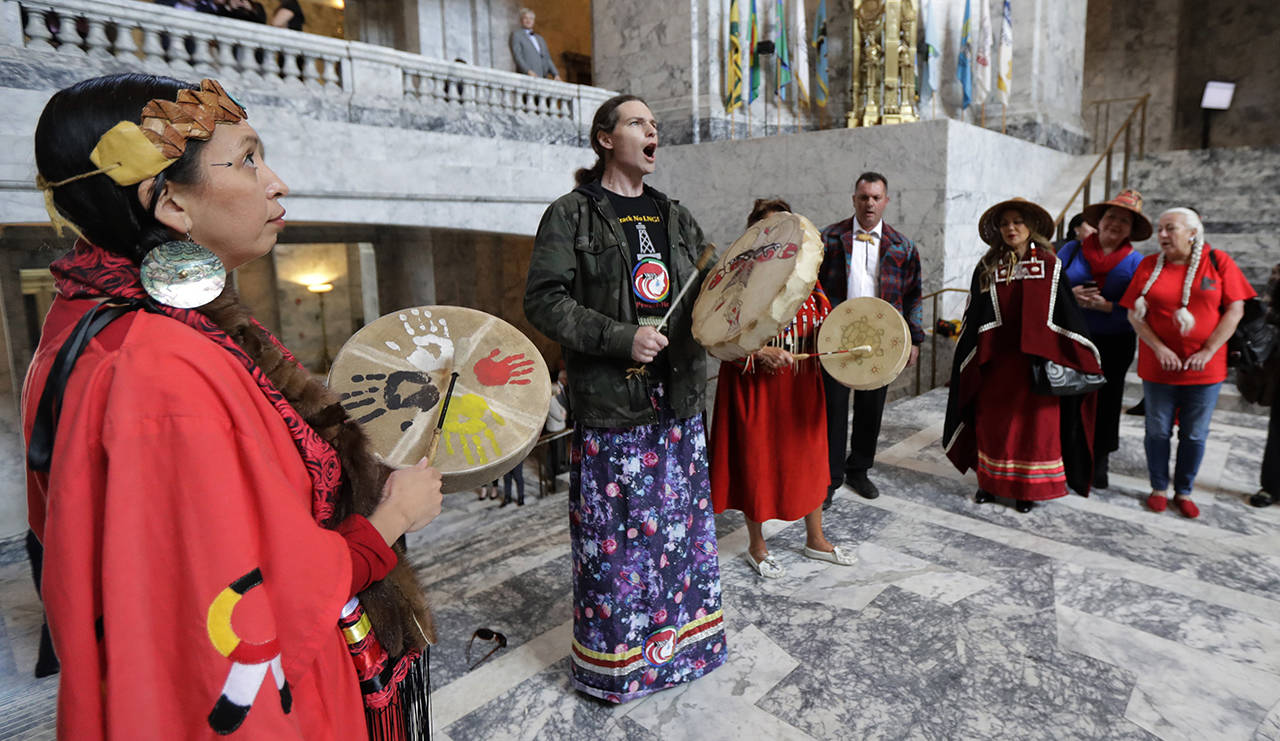 Earth Feather Sovereign (left) of the Confederated Tribes of the Colville Reservation, joins others in playing drums and signing in the Capitol Rotunda after Washington Gov. Jay Inslee signed a bill into law April 24 in Olympia. The bill creates liaison positions within the Washington State Patrol, and requires the agency to develop best practices in hopes of reducing disproportionate rates of violence faced by Native American and indigenous women, and also the frequency with which perpetrators of the crimes avoid justice. (AP Photo/Ted S. Warren)