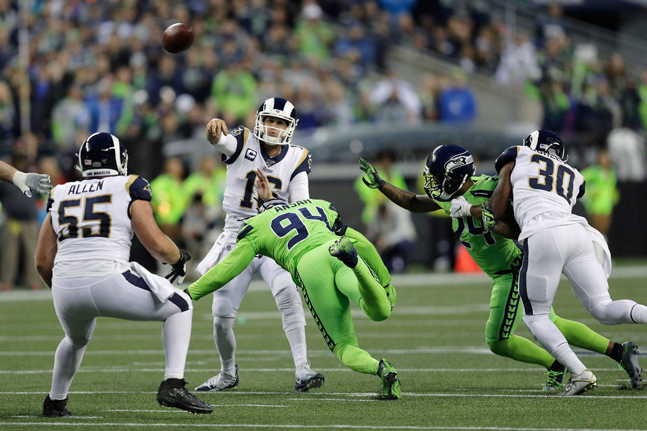 Rams quarterback Jared Goff passes under pressure from Seahawks defensive end Ziggy Ansah (94) and cornerback Jamar Taylor (24) during a game on Oct. 3, 2019, in Seattle. (AP Photo/Stephen Brashear)