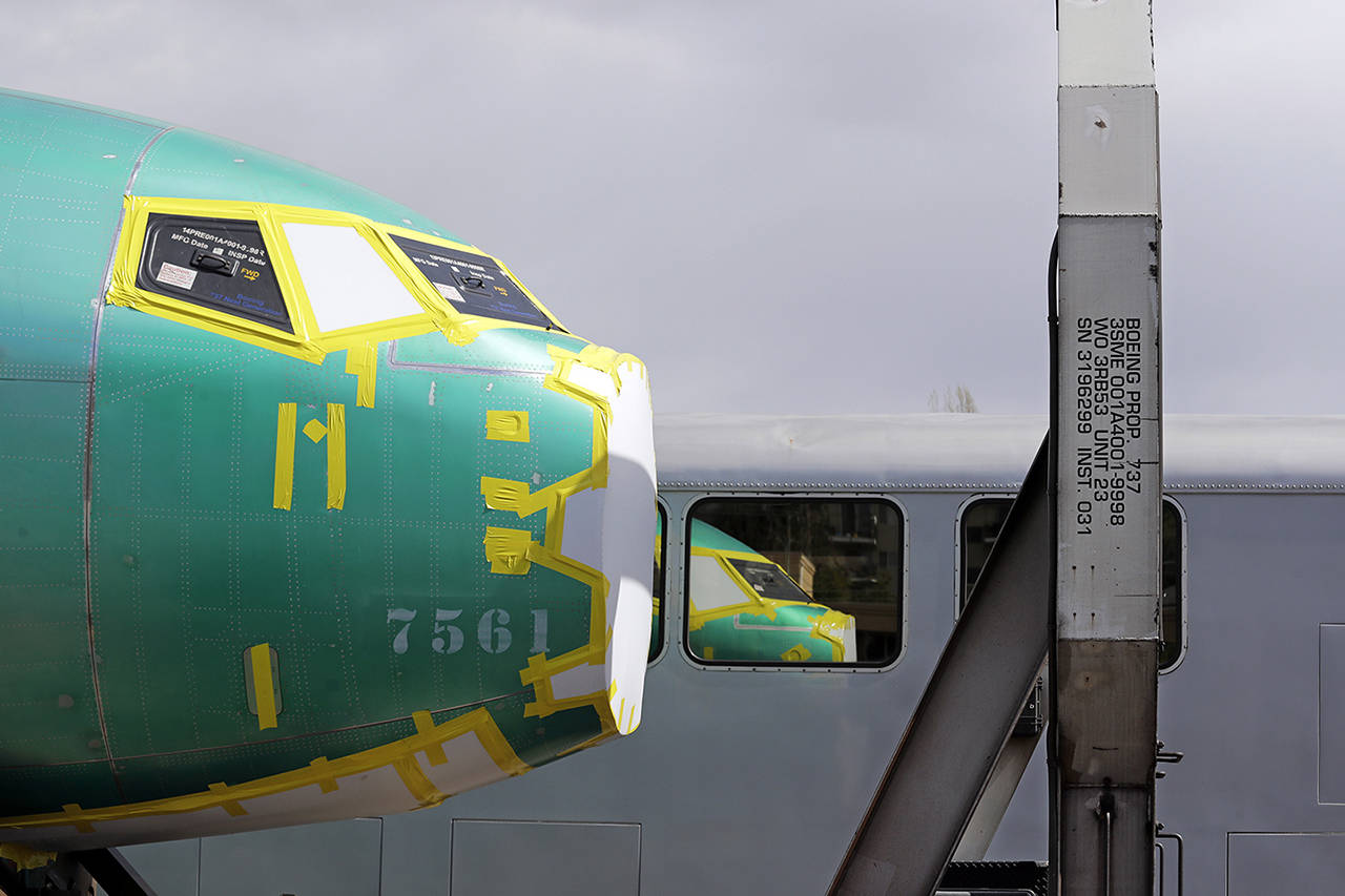 In this April 9 photo, the front of a Boeing 737 fuselage, eventually bound for Boeing’s production facility in Renton, sits on a flatcar rail car and is reflected in a nearby passenger train car at a rail yard in Seattle. (AP Photo/Elaine Thompson, File)