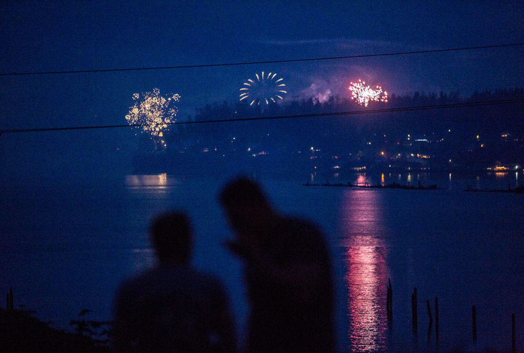 A couple at Legion Memorial Park in Everett watches fireworks set off from Priest Point in Tulalip on July 4, 2018. (Olivia Vanni / Herald file) 
A couple watches people set off fireworks from Priest Point at Everett’s Legion Memorial Park on July 4. (Olivia Vanni / Herald file)

