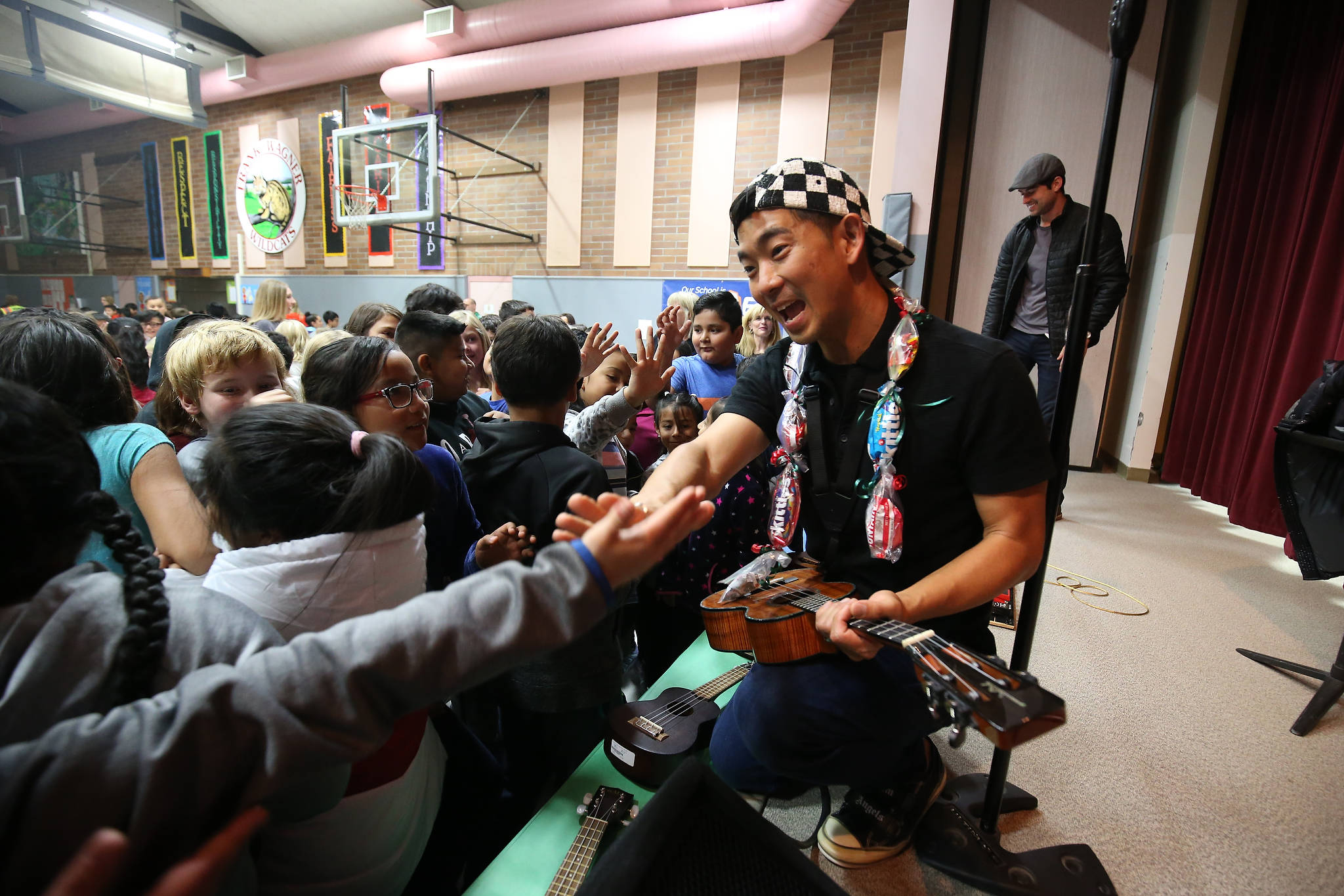 Jake Shimabukuro high-fives students and sign ukuleles after performing at Frank Wagner Elementary. (Andy Bronson / The Herald)