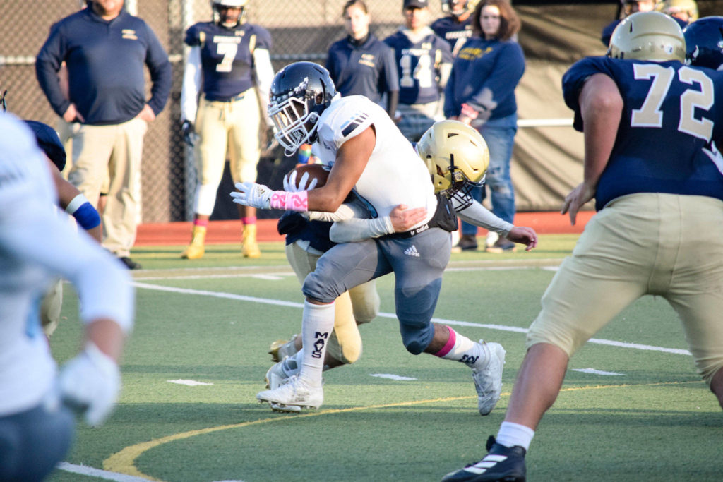 Senior running back Hussain Al-Mayyahi runs while being tackled by an Everett defender on Friday, Oct. 11 at Everett Memorial Stadium. (Katie Webber / The Herald)
