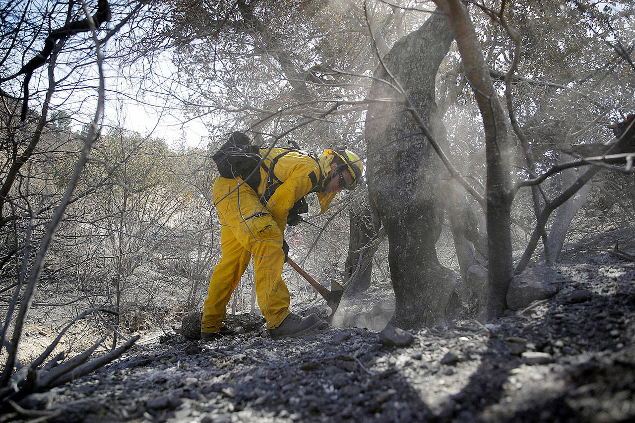 Brett Palmer, with the South Placer Fire Deptartment, looks for hotspots in the aftermath of a wildfire in Porter Ranch, California. (AP Photo/Marcio Jose Sanchez)