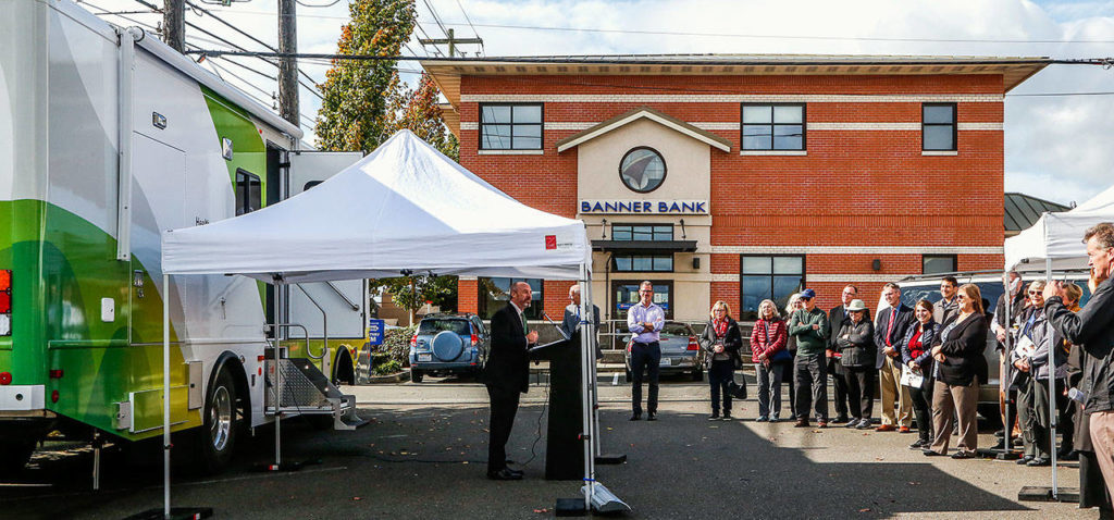Dr. John Tomkowiak, founding dean of WSU’s Elson S. Floyd College of Medicine, speaks to a crowd outside Everett’s Banner Bank on Thursday as they get a look at the new mobile medical unit operated by Range Health. (Dan Bates / The Herald)
