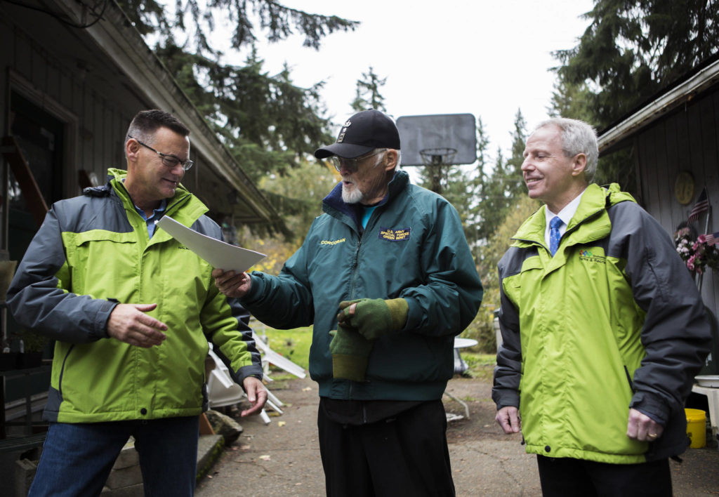 Jim Corcoran (center) passes his property deed to Snohomish County Parks, Recreation and Tourism Department director Tom Teigen (left). (Olivia Vanni / The Herald)
