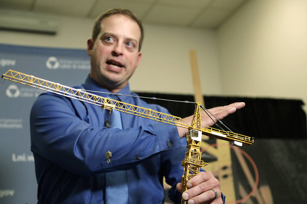 Brian Haight, crane program manager for Washington state’s Department of Labor and Industries, uses a model of a crane during a news conference Thursday in Tukwila to explain the collapse of a crane earlier in the year in Seattle that killed four people. (AP Photo/Elaine Thompson)