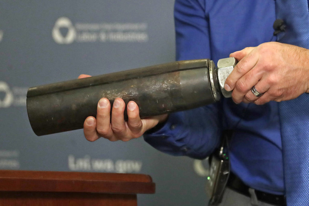 Brian Haight, Crane Program manager for Washington state’s Department of Labor and Industries, holds a 26-pound pin and sleeve of the type used in the collapse of a crane earlier in the year in Seattle that killed four people. Washington State’s L&I found, as experts have long suspected, that the crane toppled because workers who were disassembling it had prematurely removed pins securing the sections of the crane’s mast. (AP Photo/Elaine Thompson)
