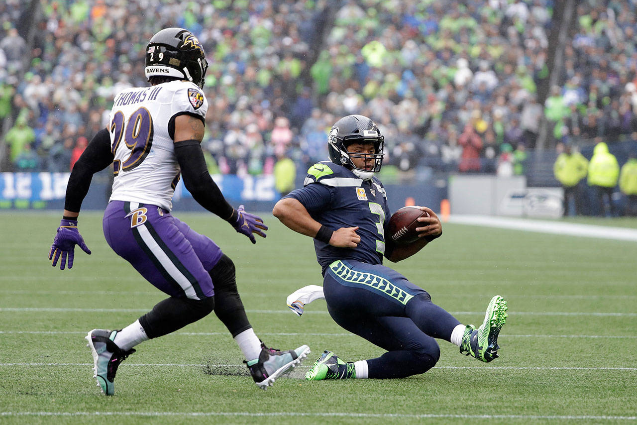 Baltimore safety Earl Thomas (left) closes in on a sliding Russell Wilson during the Ravens’ 30-16 win over the Seahawks on Sunday at CenturyLink Field in Seattle. (AP Photo/Elaine Thompson)