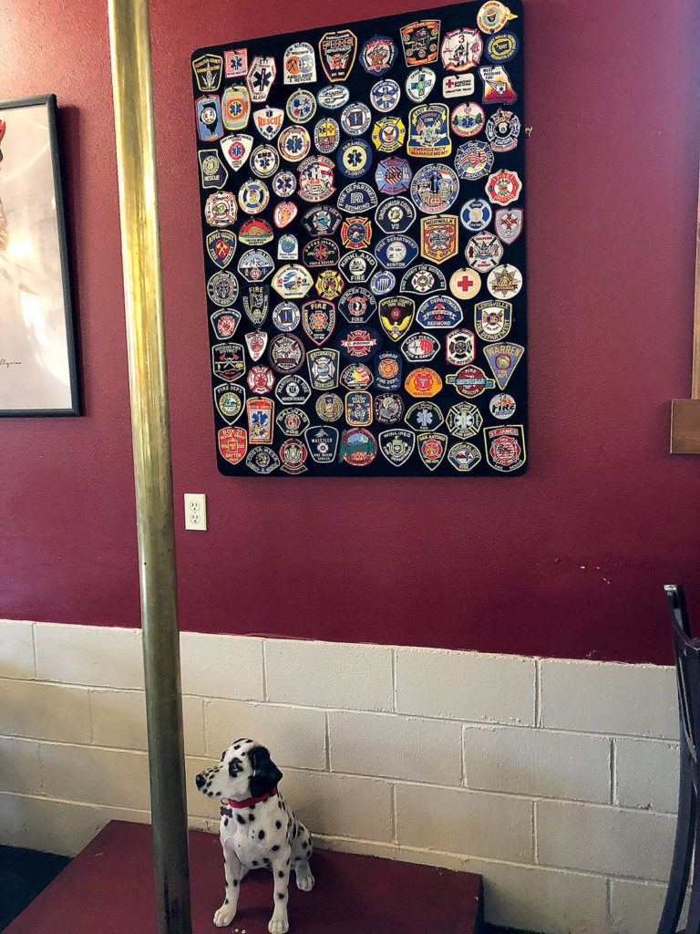 Patches from fire stations around the world hang on a wall near a firehouse pole in the restaurant of SAAL Brewing Co.’s new taproom and restaurant. (Aaron Swaney)

