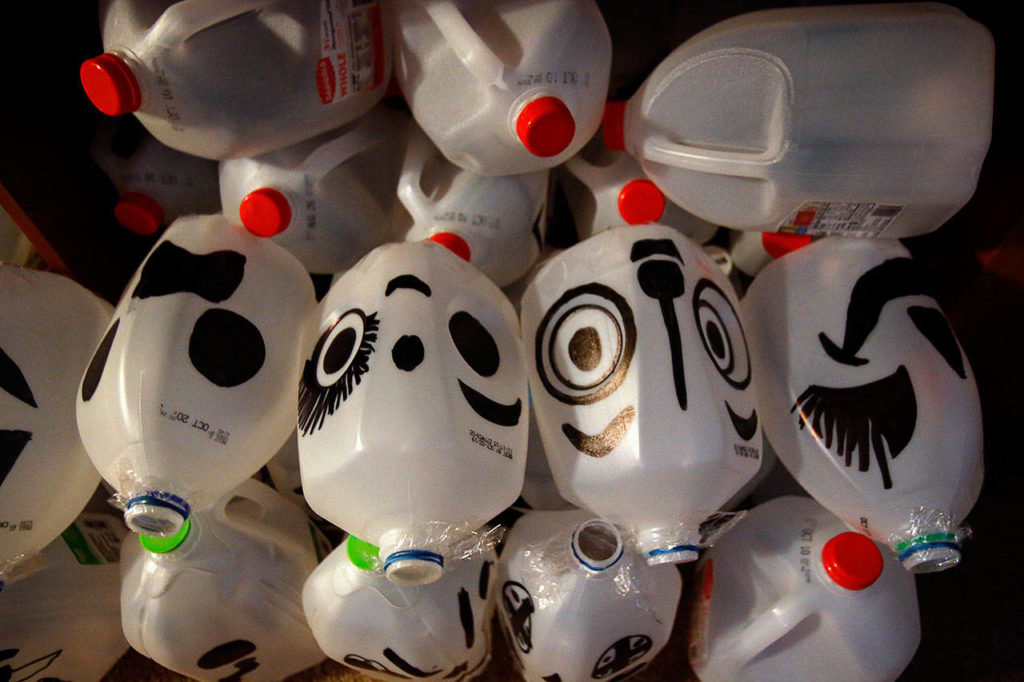 Using black markers, Ivy Fulmer made 102 ghost faces from milk jugs. With lights inside, they’ll illuminate the way through the yard for the kids. (Dan Bates / The Herald)
