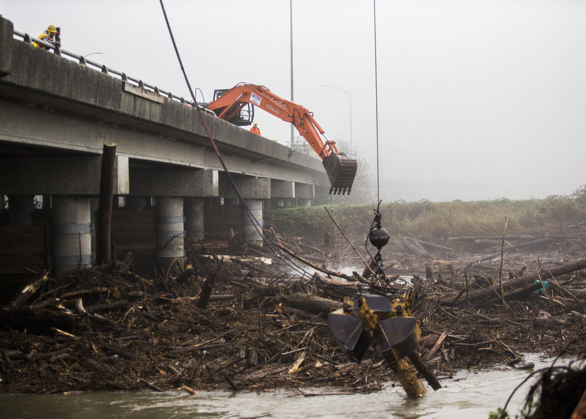 An excavator clears logs along the eastbound lanes of the U.S. 2 trestle on Wednesday between Everett and Lake Stevens. (Olivia Vanni / The Herald)