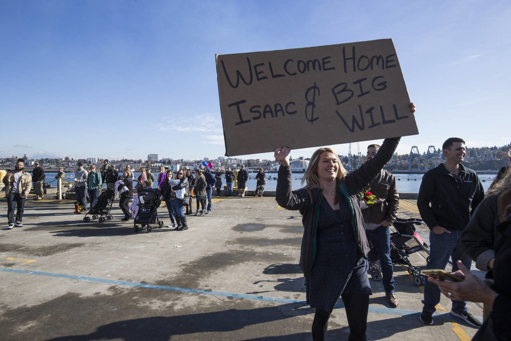 Sydney O’Neil holds up a sign welcoming her boyfriend, Isaac Cales, and fellow sailor William Hernandez as the USS Momsen (DDG-92) returns to Naval Station Everett after a deployment to the Pacific on Monday in Everett. (Andy Bronson / The Herald)
