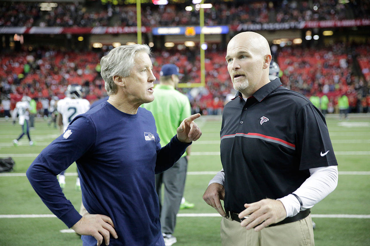Seahawks head coach Pete Carroll (left) speaks with Falcons head coach Dan Quinn before a playoff game on Jan. 14, 2017, in Atlanta. (AP Photo/David Goldman)