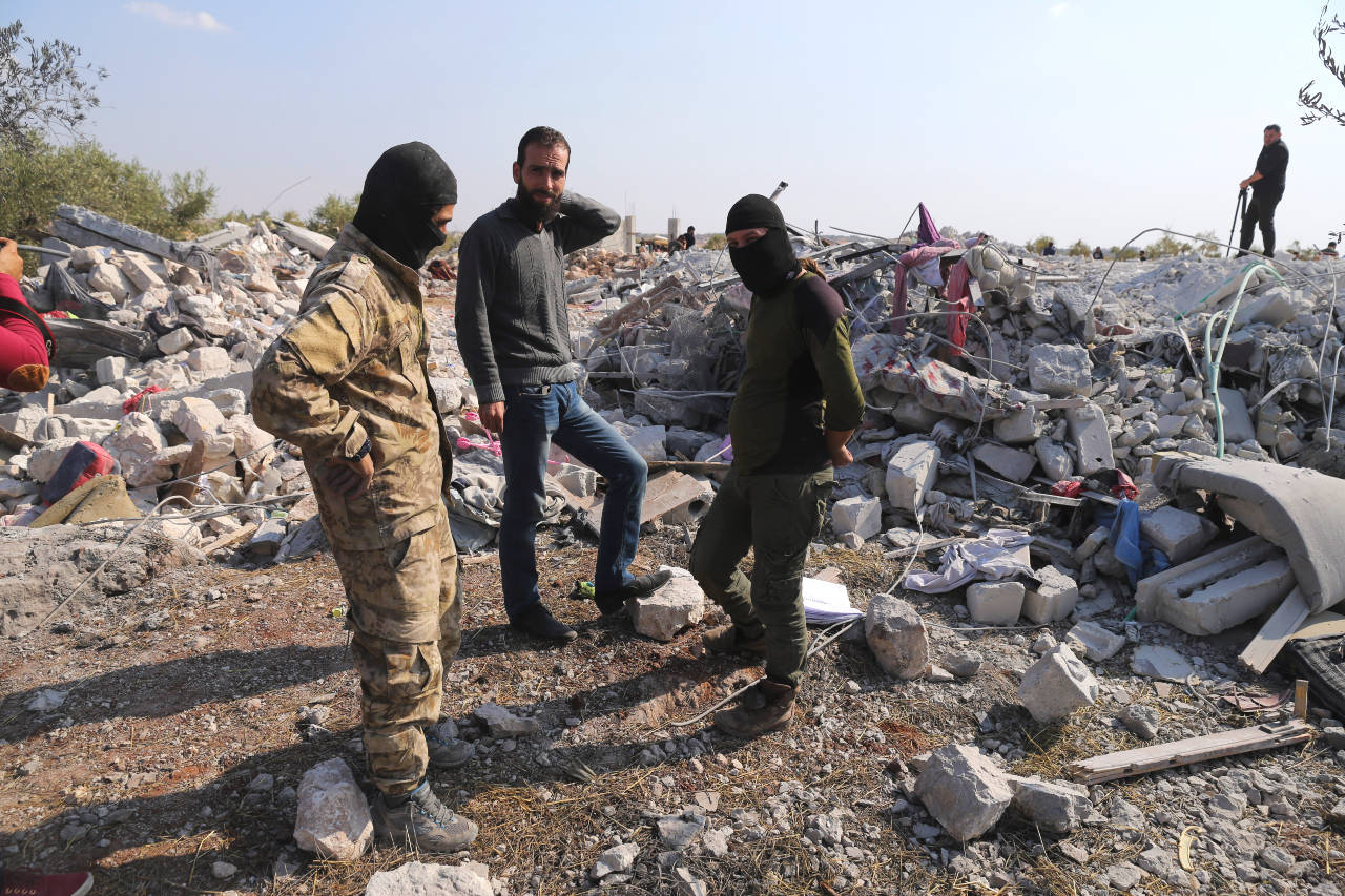 People look at a destroyed houses near the village of Barisha, in Idlib province, Syria, Sunday, after an operation by the U.S. military which targeted Abu Bakr al-Baghdadi, the shadowy leader of the Islamic State group. President Donald Trump says Abu Bakr al-Baghdadi is dead after a U.S. military operation in Syria targeted the Islamic State group leader. (AP Photo/Ghaith Alsayed)