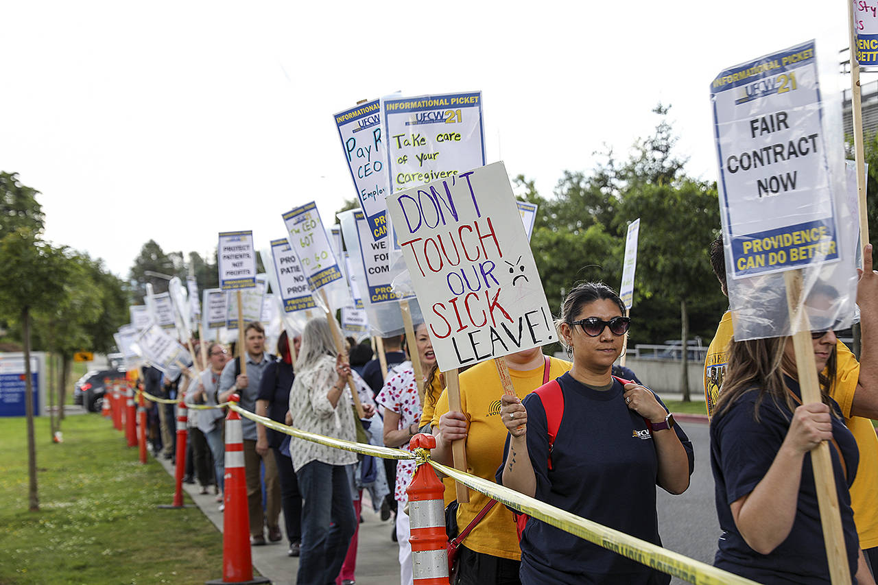 Workers and supporters protested against proposed cuts of benefits outside Providence Regional Medical Center Everett in June. (Lizz Giordano / The Herald)