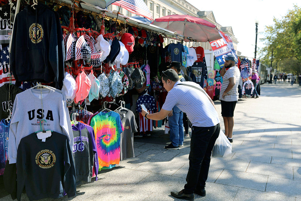 A Chinese tourist takes pictures of t-shirts at a tourism kiosk in Washington, D.C., on Oct. 15. Across the country, the U.S. tourism industry is trying to counter one of the casualties of the trade war with China that is still raging despite this month’s temporary truce: A drop in the flow of affluent Chinese visitors to the U.S. (AP Photo/ Bani Sapra)