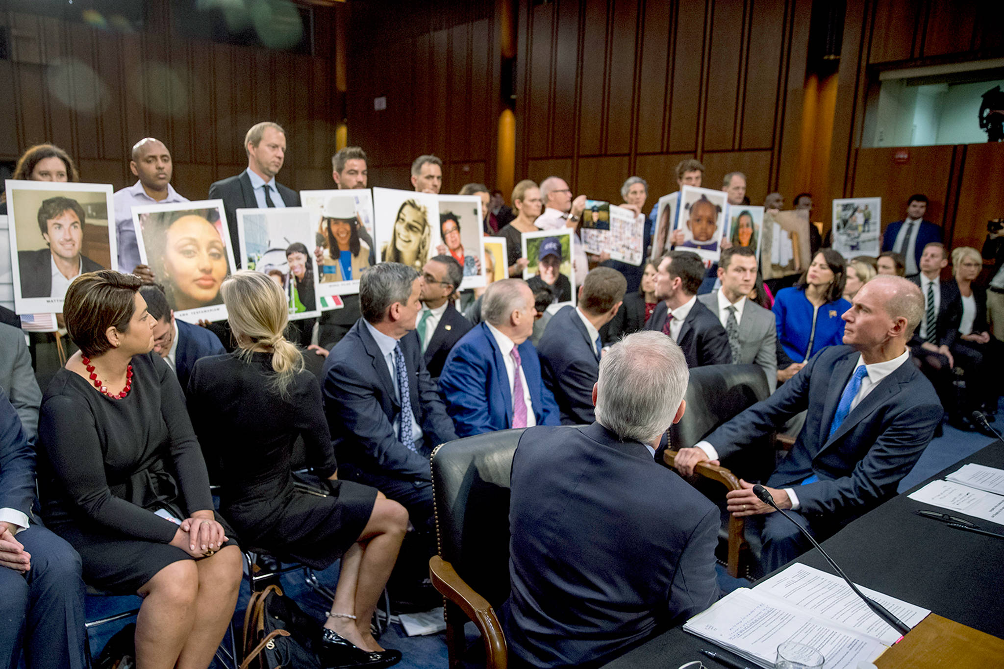 Boeing Company President and Chief Executive Officer Dennis Muilenburg (right) watches as family members hold up photographs of those killed in the Ethiopian Airlines Flight 302 and Lion Air Flight 610 crashes during a Senate Transportation Committee hearing on Boeing’s 737 Max on Capitol Hill in Washington on Tuesday. (AP Photo/Andrew Harnik)
