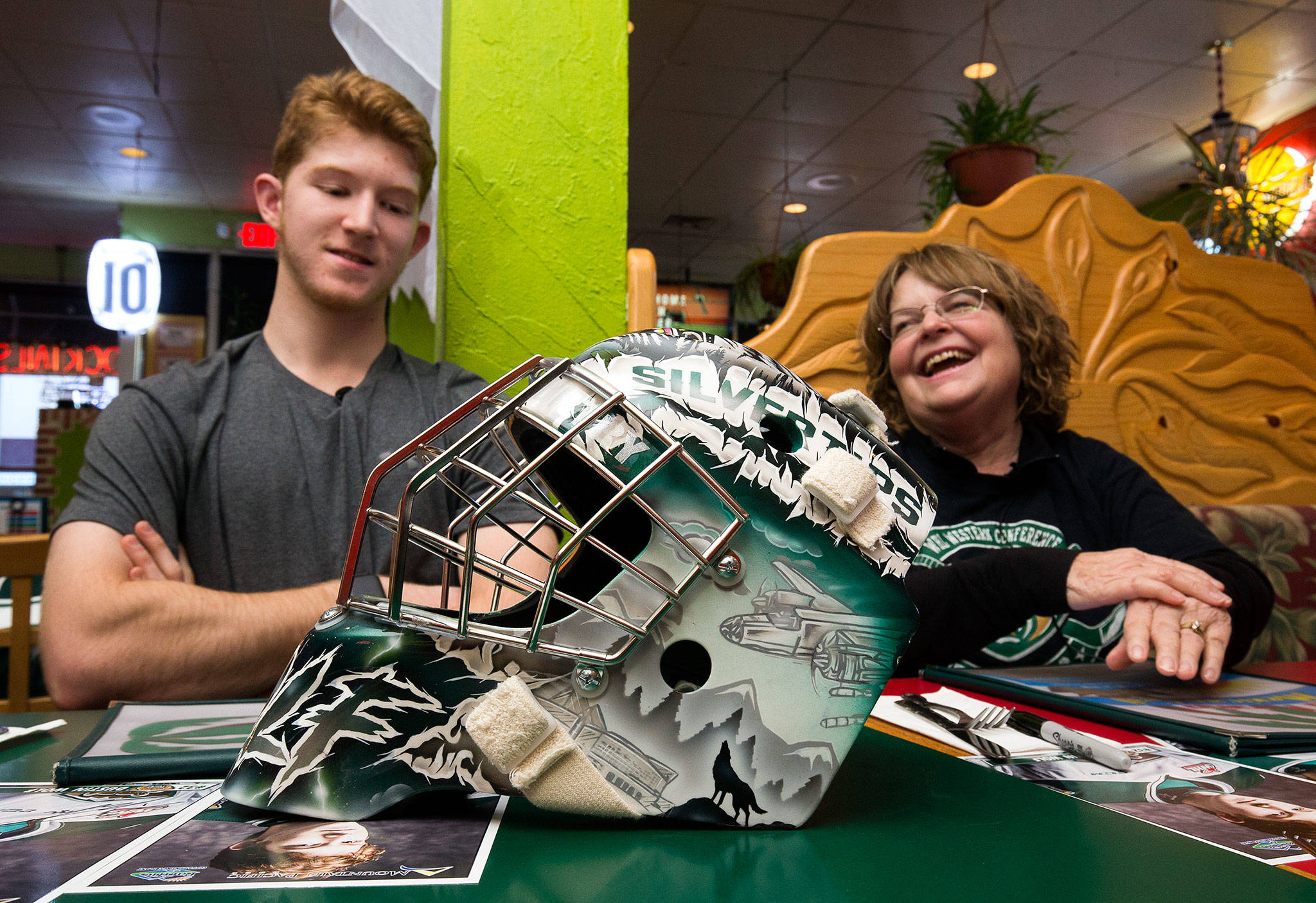 Nancy Wilds, right, laughs with Silvertips goalie Dustin Wolf over dinner on Monday, Oct. 28, 2019 in Everett, Wash. Wilds was the design winner for Wolf’s mask and was treated with dinner with the goalie. (Andy Bronson / The Herald)