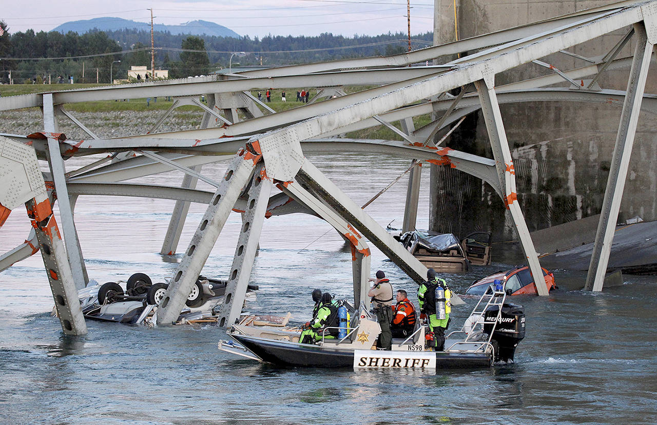 A boat crew examines a upside down car in the Skagit River after the I-5 bridge collapsed in May 2013. (Jennifer Buchanan / Herald file)