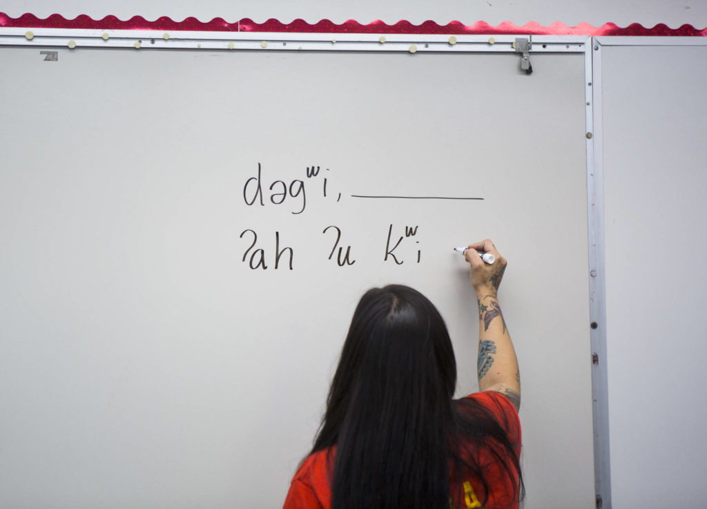 Natosha Gobin writes Lushootseed phrases on the white board to be used in a game of Go Fish. (Olivia Vanni / The Herald)
