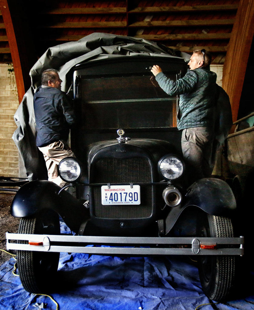Ruben Sanchez (left), and Doug Acheson, both with Everett’s facilities department, remove a tarp from Everett’s vintage bookmobile, Pegasus, on Tuesday. Stored in a large utility building south of Thornton A. Sullivan Park at Silver Lake, the bookmobile may eventually be on display at the Everett Museum of History. (Dan Bates / The Herald)
