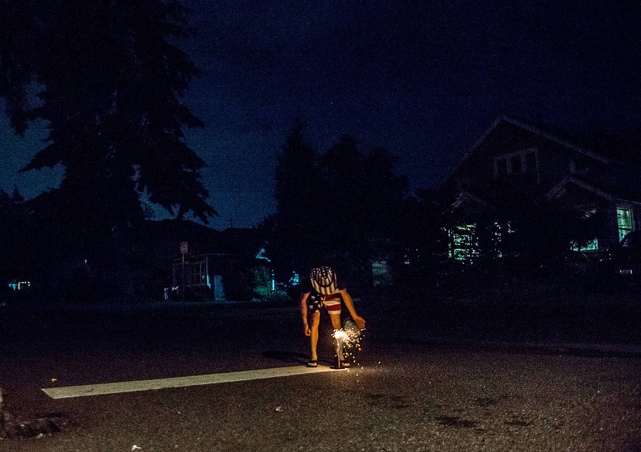 Jeffery Kasch lights off fireworks in the Pinehurst neighborhood on July 4, 2018, in Everett. (Olivia Vanni / Herald file)