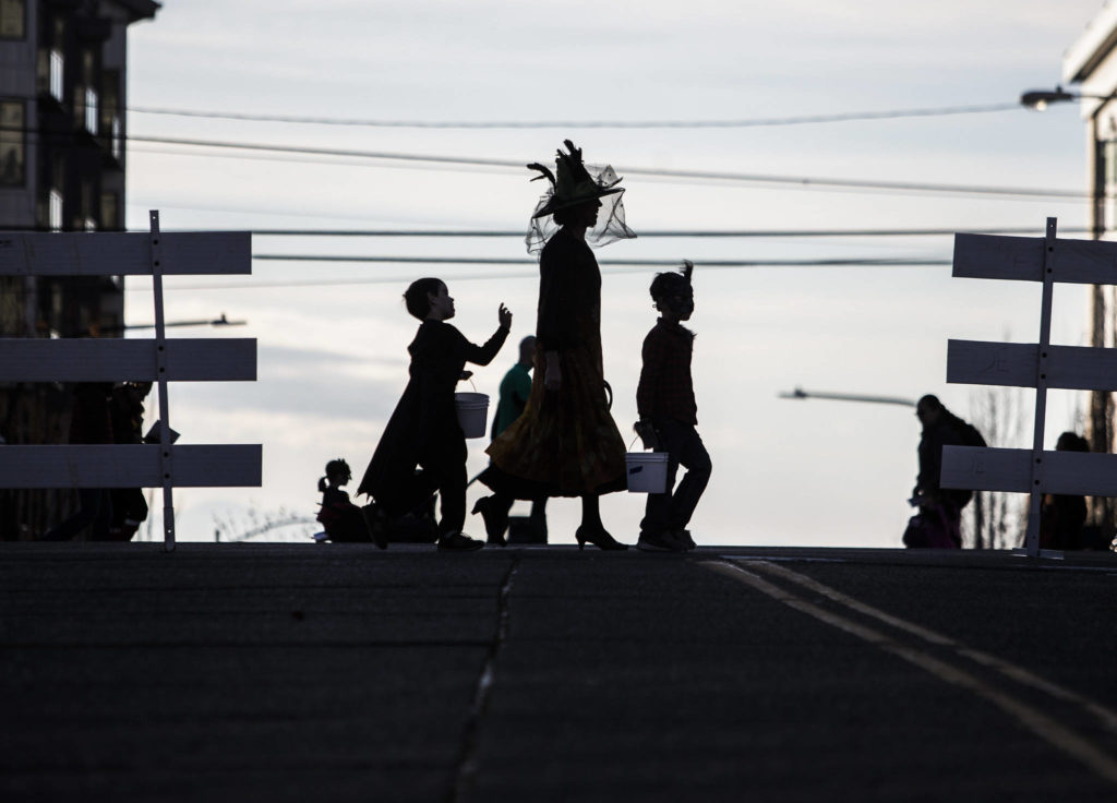 A family in costume crosses California Street during downtown trick-or-treating Thursday in Everett. (Olivia Vanni / The Herald)
