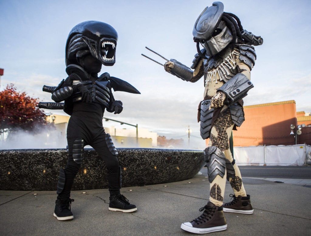 Gavin Brown, 8, dressed as Alien, and Kaleb Brown, 11, dressed as Predator, went trick-or-treating in costumes made by their dad during downtown trick-or-treating Thursday in Everett. (Olivia Vanni / The Herald)
