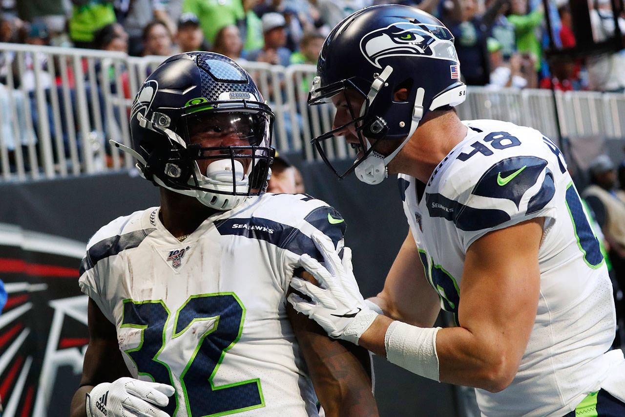 Seahawks running back Chris Carson (32) celebrates his touchdown with tight end Jacob Hollister (48) during the first half of a game against the Falcons on Oct. 27, 2019, in Atlanta. (AP Photo/John Bazemore)