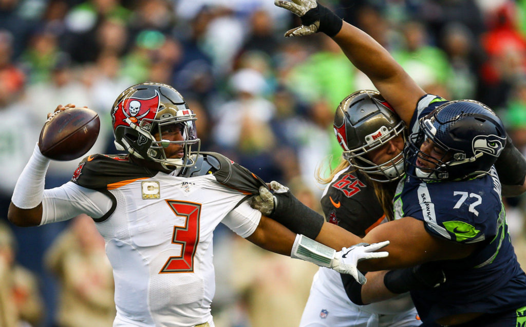 Buccaneers Jameis Winston with the help of teammate Alex Cappa works free of Seahawks Al Woods Sunday afternoon at CenturyLink Field in Seattle on November 3, 2019. (Kevin Clark / The Herald)
