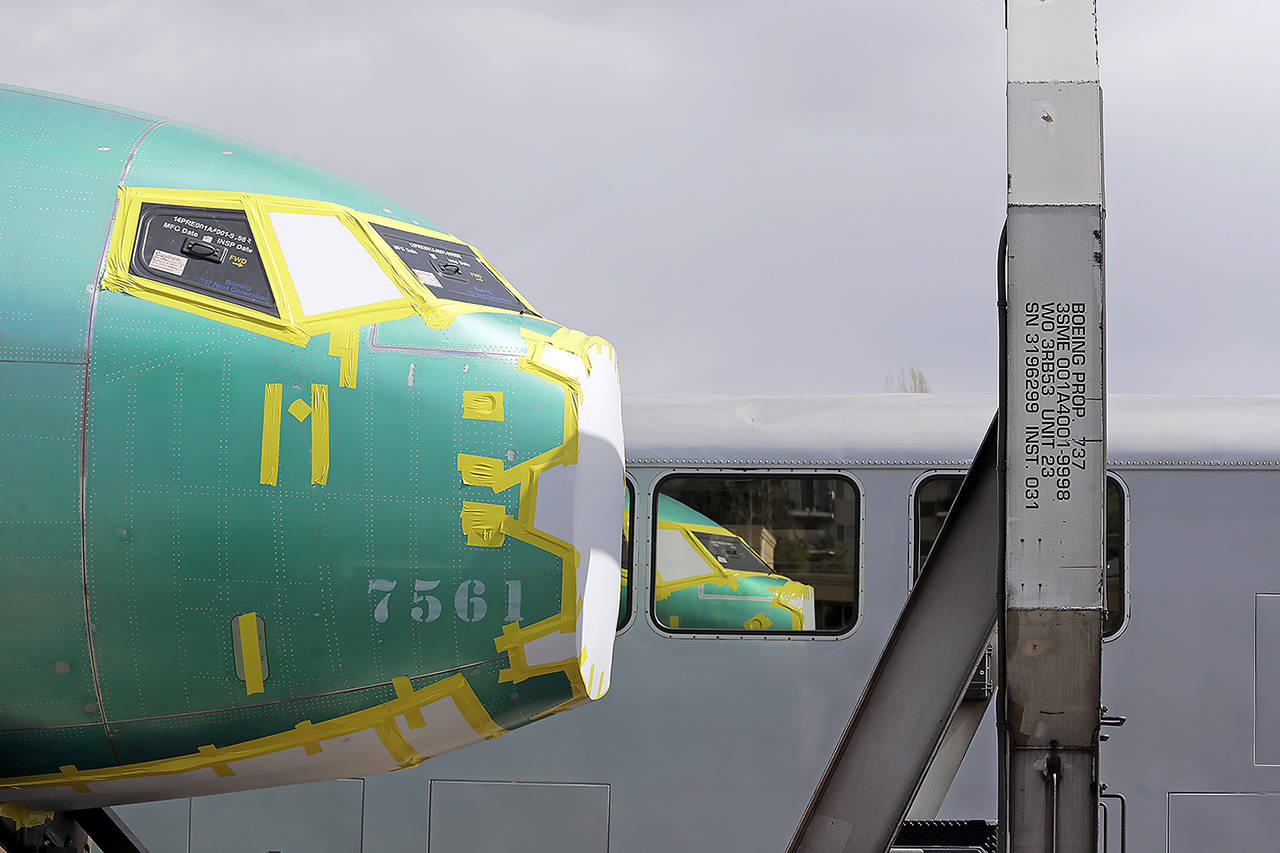 In this April 9 photo, the front of a Boeing 737 fuselage sits on a flatcar rail car and is reflected in a nearby passenger train car at a rail yard in Seattle. (AP Photo/Elaine Thompson, File)