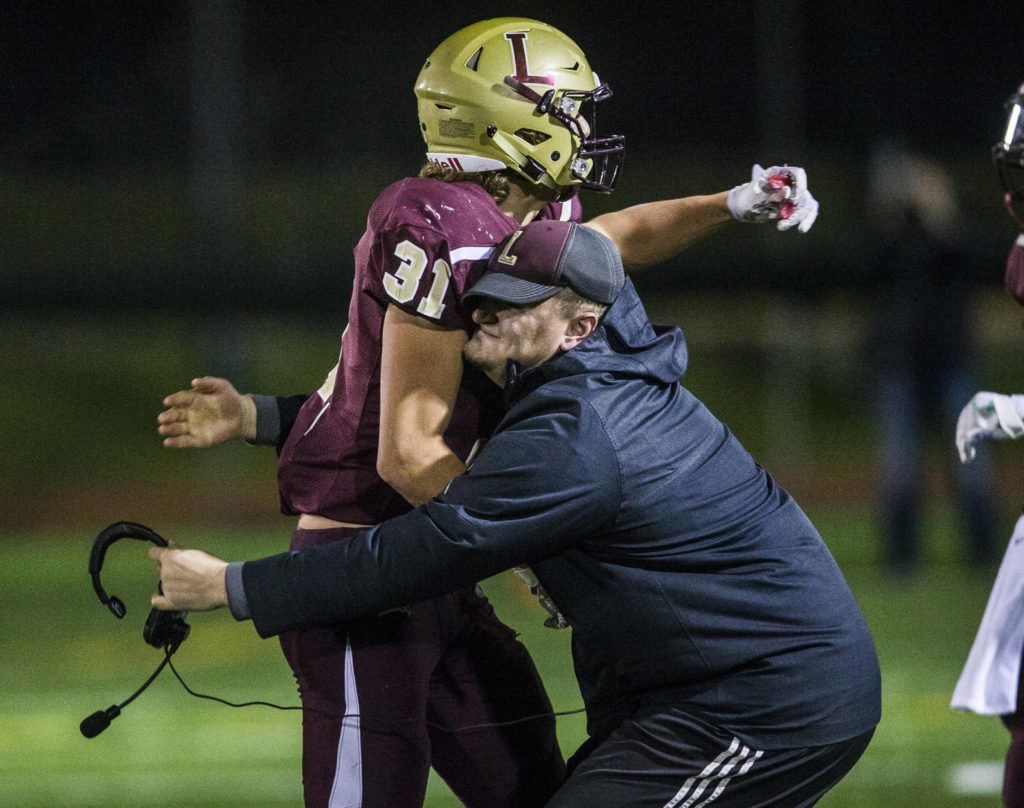 Lakewood’s Riley Krueger is picked up by a coach as they celebrate on the sidelines during a 2A playoff game against Liberty on Nov. 8, 2019 in Arlington, Wash. (Olivia Vanni / The Herald)

