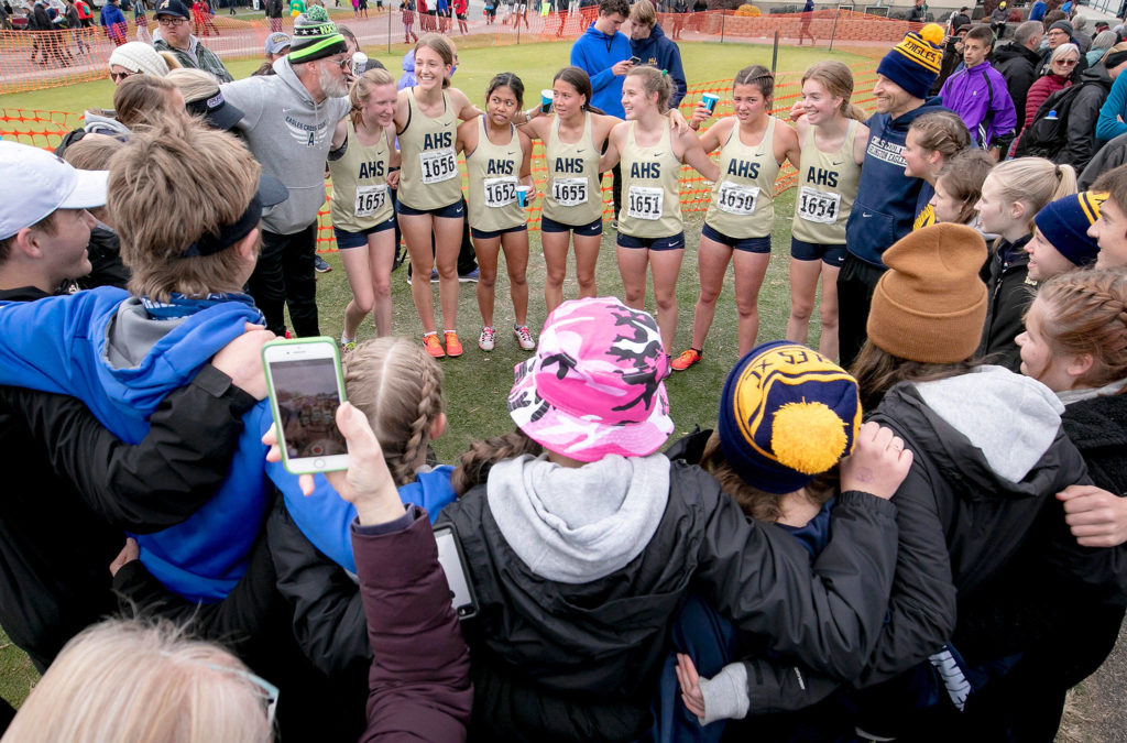 Arlington head coach Mike Shierk (left of team) congratulates his girls team after its program-best fifth-place state finish. (TJ Mullinax / for The Herald)
