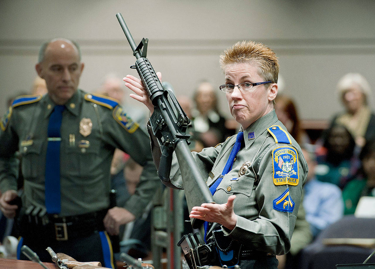 Firearms training unit Detective Barbara J. Mattson, of the Connecticut State Police, holds up a Bushmaster AR-15 rifle, the same make and model of gun used by Adam Lanza in the Sandy Hook School shooting, for a demonstration during a hearing of a legislative subcommittee reviewing gun laws, at the Legislative Office Building in Hartford, Connecticut, on Jan. 28, 2013. The Supreme Court said Tuesday, Nov. 12, 2019, a survivor and relatives of victims of the Sandy Hook Elementary School shooting can pursue their lawsuit against the maker of the rifle used to kill 26 people. (AP Photo/Jessica Hill, File)