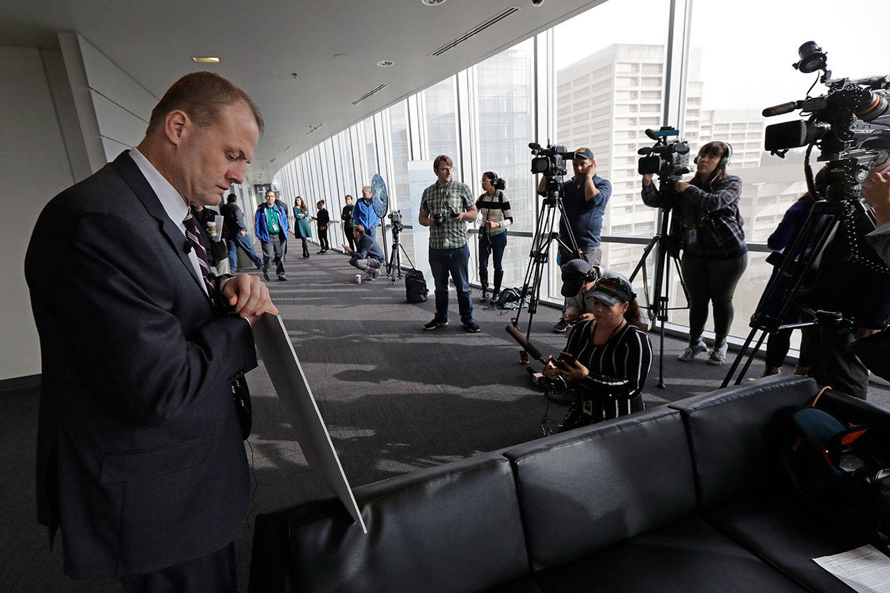 Anti-tax activist Tim Eyman leans on a sign as he prepares to talk to reporters, Nov. 7, outside the office of Seattle Mayor Jenny Durkan in Seattle. (Ted S. Warren / Associated Press)