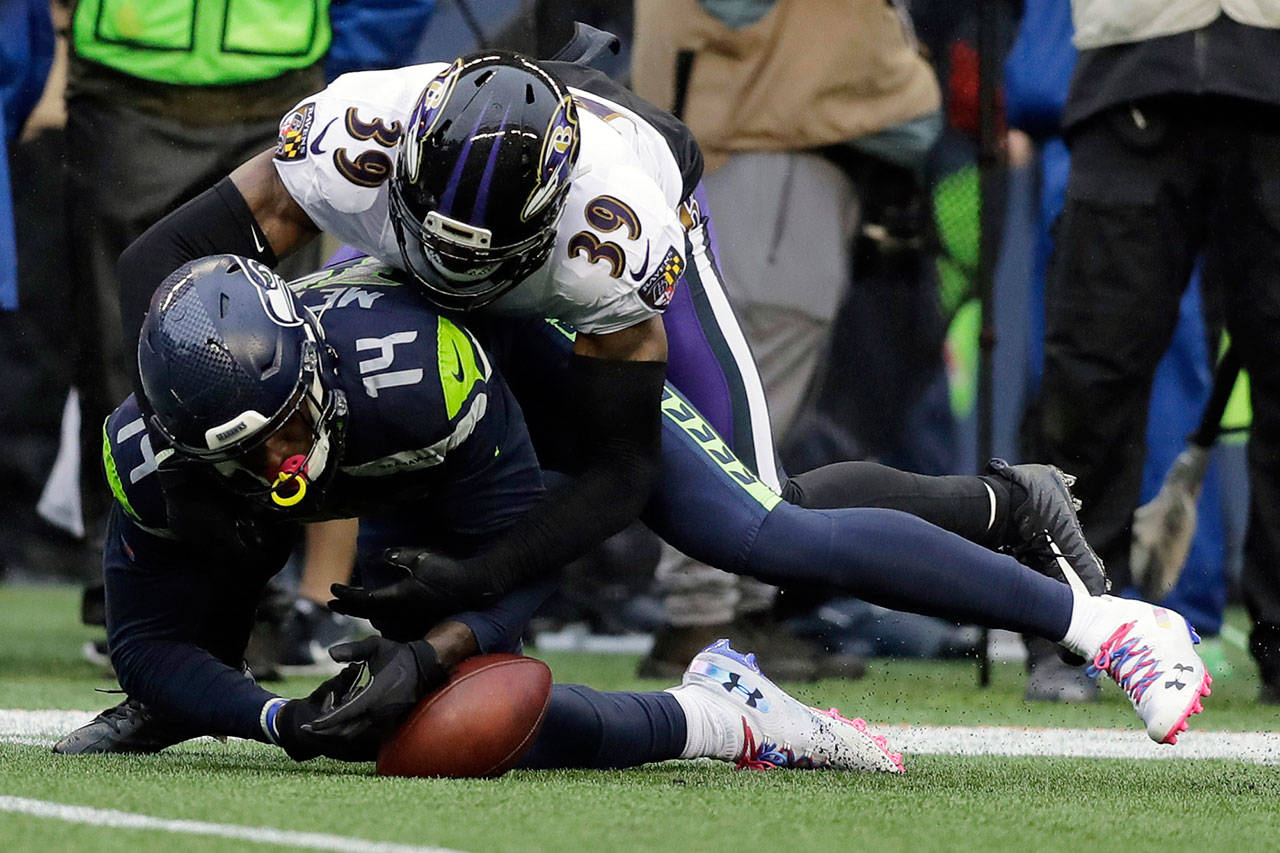 Seahawks wide receiver D.K. Metcalf (14) fumbles as he is hit by Ravens cornerback Brandon Carr (39) during the second half of a game Oct. 20, 2019, in Seattle. (AP Photo/John Froschauer)