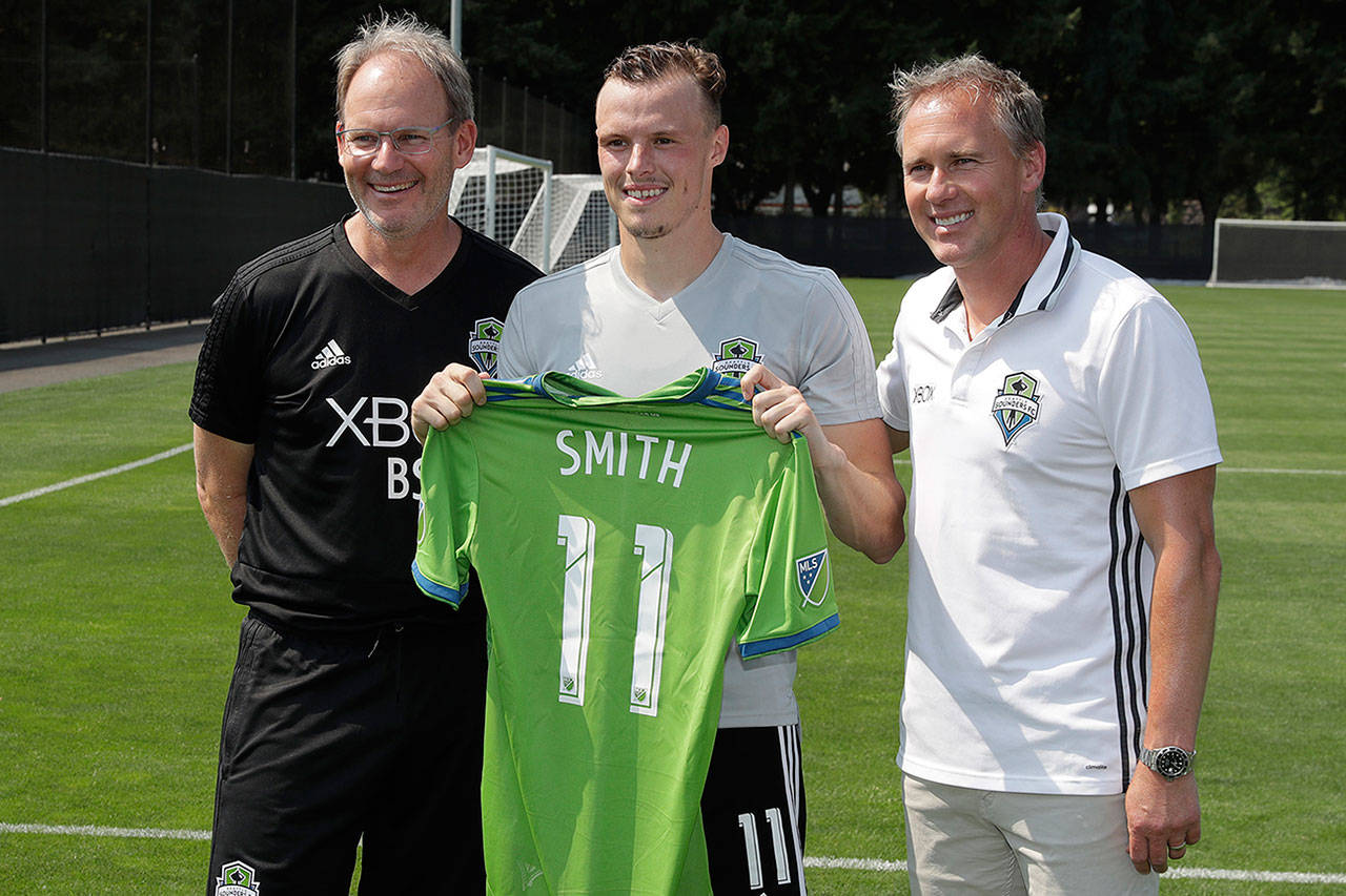 Seattle Sounders vice president of soccer and sporting director Chris Henderson (right) poses with defender Brad Smith (11) and head coach Brian Schmetzer following a training session in August of 2018. (AP Photo/Ted S. Warren)