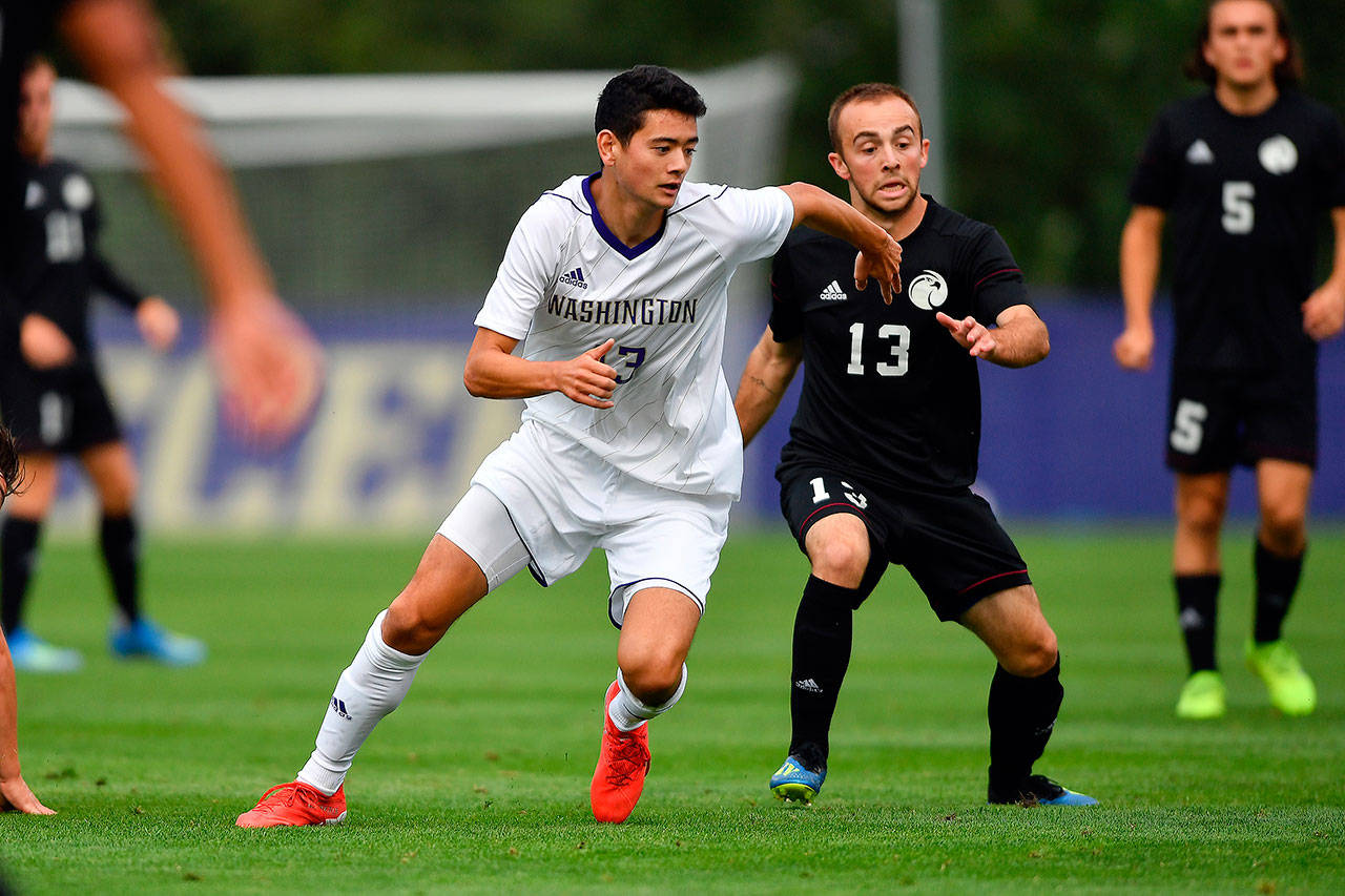 The University of Washington’s John Magnus (left) fights off a defender during a match earlier this season at Husky Soccer Stadium in Seattle. (University of Washington photo)