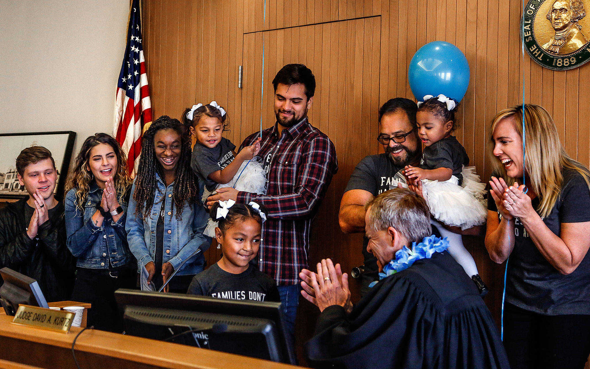 Arlington’s Avellaneda family join Judge David Kurtz at his bench as Mayah, 6, strikes his gavel Friday, National Adoption Day. Mayah and her two younger sisters, Alayna, 2, and Malaya, 1, were adopted by Jen (right) and Cid Avellaneda (next to Jen). Other family members are (from left) the Avellanedas’ son-in-law, Blake King, their daughter, Mariah King, their other adopted daughter, Nicole, 13, and their son, Jeriah Avellaneda, 26, holding Alayna. (Dan Bates / The Herald)