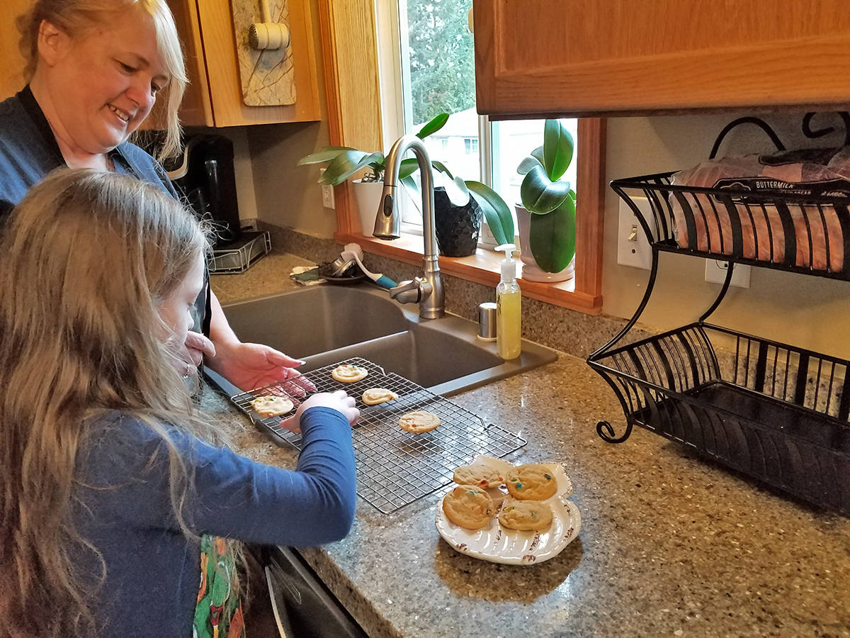 Julie Zyph and her granddaughter transfer fresh-baked cookies to a plate sitting on Zyph’s countertops. The surfaces, replaced by Granite Transformations of North Seattle, are holding up extremely well even after years of daily use, she says.