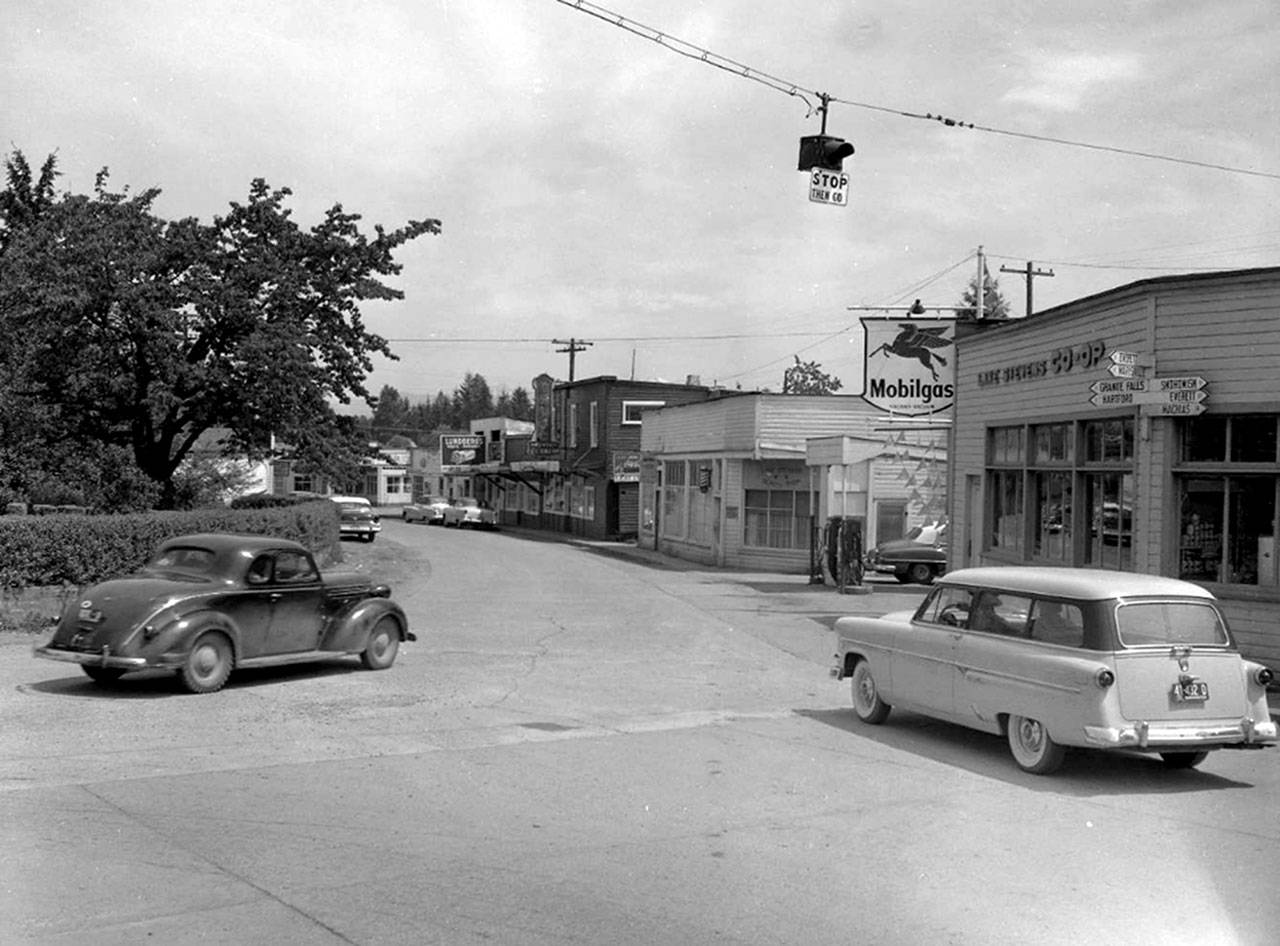 Old downtown Lake Stevens. Included in this image are the Lake Stevens Beauty shop, Irene’s Coffee Shop, a Mobilgas station and the Lake Stevens Co-op. On the side of the Co-op building is a sign-post with seven signs pointing towards the direction of and number of miles to nearby towns. (Jim Leo / The Herald, 1955)