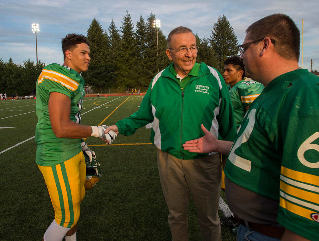 Tumwater’s Thomas Drayton (left) and a well-wisher congratulate former Thunderbirds coach Sid Otton after the field was renamed in his honor in 2017. (Drew Perine / The Olympian)
