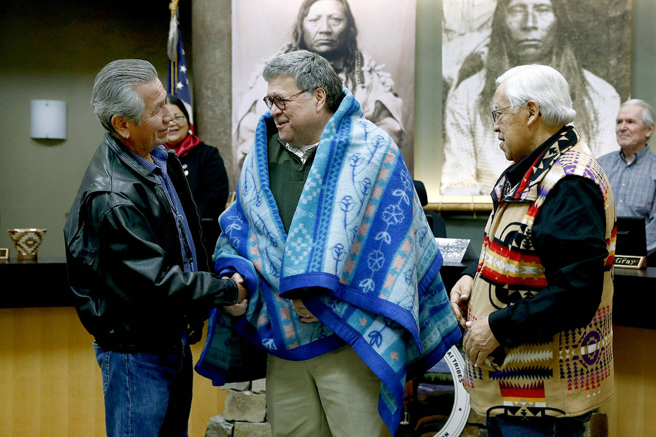 Attorney General William Barr (center) shakes hands with Vernon Finley (left) and Tony Incashola (right) after they presented him with a blanket during a Confederated Salish and Kootenai Tribes council meeting Friday on the Flathead Reservation in Pablo, Montana. (AP Photo/Patrick Semansky)